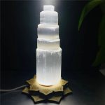 Candeeiro de selenite em forma de torre com base decorativa em forma de mandala, iluminado, com detalhes translúcidos e textura natural da selenite.