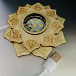 Candeeiro de selenite com estrutura em forma de mandala, com LEDs visíveis no centro e cabo USB conectado na parte inferior.
