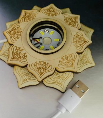 Candeeiro de selenite com estrutura em forma de mandala, com LEDs visíveis no centro e cabo USB conectado na parte inferior.