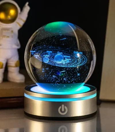Globo de ciência com sistema solar em miniatura, projeção de estrelas e planetas, base iluminada, ambiente de estudo ou decoração educativa.