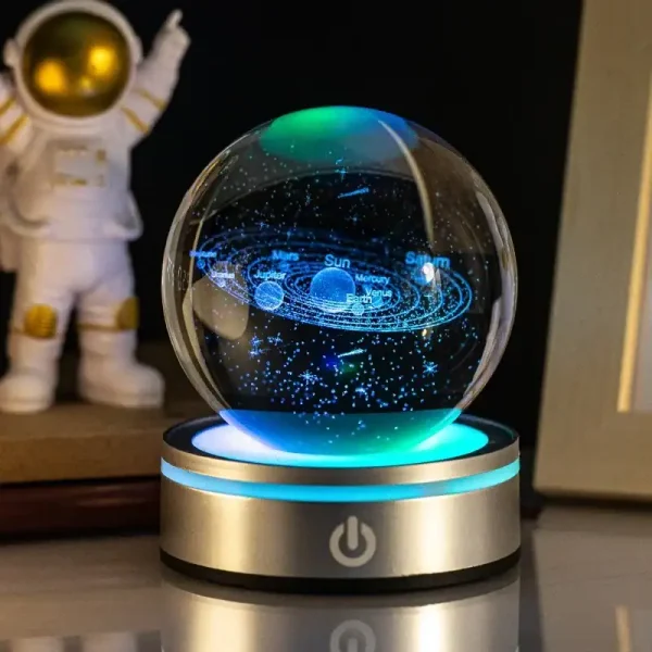 Globo de ciência com sistema solar em miniatura, projeção de estrelas e planetas, base iluminada, ambiente de estudo ou decoração educativa.