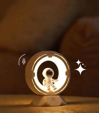 Lâmpada de plasma com figura de astronauta no centro, iluminação brilhante e detalhes de estrelas ao lado, sobre uma superfície de madeira.