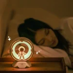 Luz de leitura com design de astronauta em miniatura, emitindo luz suave, ao lado de uma mulher a dormir, ambiente acolhedor e escuro.
