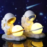 Duas figuras de astronautas com capacetes dourados, segurando planetas luminosos em uma base de rocha, com fundo de céu estrelado e cometa.