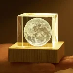 Lâmpada decorativa com base de madeira, esfera de vidro com imagem da lua, iluminação suave, ideal para decoração científica ou educativa.