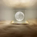 Lâmpada de plasma com forma da lua, iluminada, colocada sobre uma base de madeira, com fundo neutro e iluminação suave.