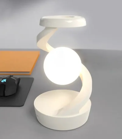 Luminária de mesa com estrutura em espiral e esfera luminosa no centro, em ambiente de escritório.