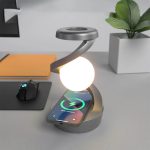 Lâmpada LED branca em forma de espiral com suporte circular, iluminando uma mesa de escritório com smartphone carregando.