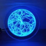 Disco de plasma azul com padrões de descargas elétricas visíveis, iluminado no escuro, mostrando as linhas de energia dentro do dispositivo.