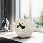 Lâmpada de plasma branca com desenho de rosto sorridente, colocada numa mesa de madeira perto de uma janela com luz natural.