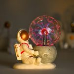 Miniatura de astronauta sentado ao lado de uma lâmpada de plasma acesa, com relâmpagos visíveis dentro do globo de vidro.
