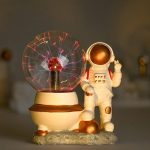 Miniatura de astronauta ao lado de esfera de plasma com relâmpagos visíveis, em base decorativa.