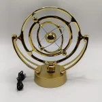 Modelo de sistema solar em metal dourado com órbitas e planetas suspensos, base circular e cabo de ligação.