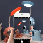 Luminária de mesa com duas luzes LED, uma vermelha e uma azul, com design futurista e detalhes em forma de robô.