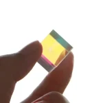Pequena lâmpada de plasma com cores vibrantes, vista de perto na mão de uma pessoa, mostrando detalhes do vidro e cores internas.