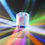 Prisma de cristal hexagonal transparente que projeta raios de luz coloridos em várias direções, criando um efeito de dispersão de cores no ambiente.