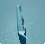 Cristal de vidro transparente com reflexão e sombra no fundo azul claro.