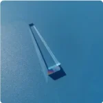 Lâmpada de plasma com tubo de vidro transparente, interior com filamento de luz azul, colocada sobre superfície azul, com sombra visível.