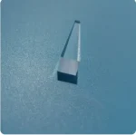 Lâmpada de plasma com forma cilíndrica, exibindo uma luz azul brilhante, colocada sobre uma superfície azul com textura suave.