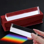 Lupa de espectro de luz visível com visor de vidro e base vermelha, mostrando um feixe de luz que projeta um espectro de cores no fundo preto.