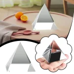 Pequena pirâmide de vidro com superfície refletora, vista de diferentes ângulos, com uma mão segurando uma versão menor da pirâmide.