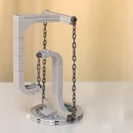Estrutura de cadeia de blocos de plástico cinza com suporte em forma de 'L' e duas correntes penduradas, usado para demonstrações educativas de física ou engenharia.