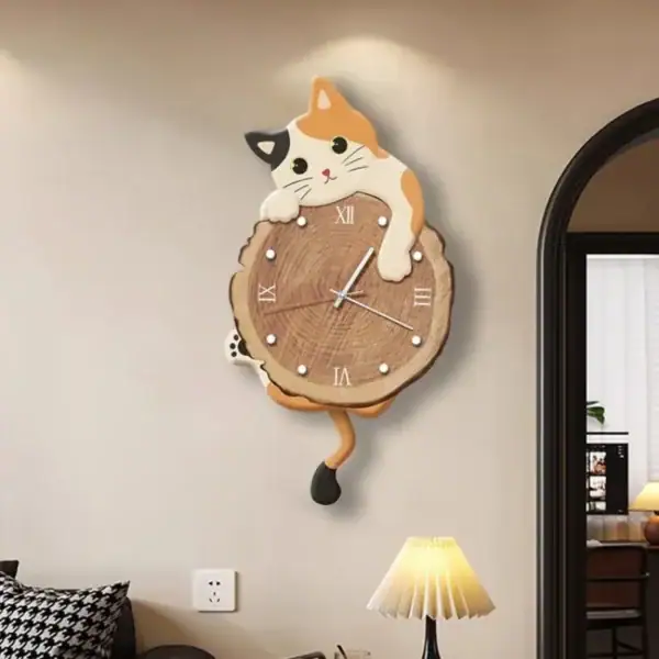 Relógio de parede com design de gato de madeira, com detalhes em cores brancas, pretas e laranja, pendurado numa parede clara ao lado de uma lâmpada de mesa.