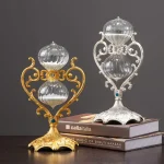 Dois candelabros decorativos, um dourado e um prateado, com detalhes ornamentais e base elaborada, colocados sobre livros.