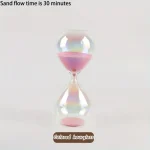 Relógio de areia com areia rosa e transparente, mostrando o fluxo de areia em 30 minutos, com fundo branco.