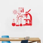 Decoração de parede com elementos científicos, incluindo microscópio, tubos de ensaio, moléculas e símbolo atómico em vermelho.