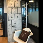 Quadro com elementos do quadro peri, cadeira com almofada de estrutura qu, e cabide de parede com ganchos de madeira, ambiente de escrit, estilo moderno e cient, decora de escrit de cincia.
