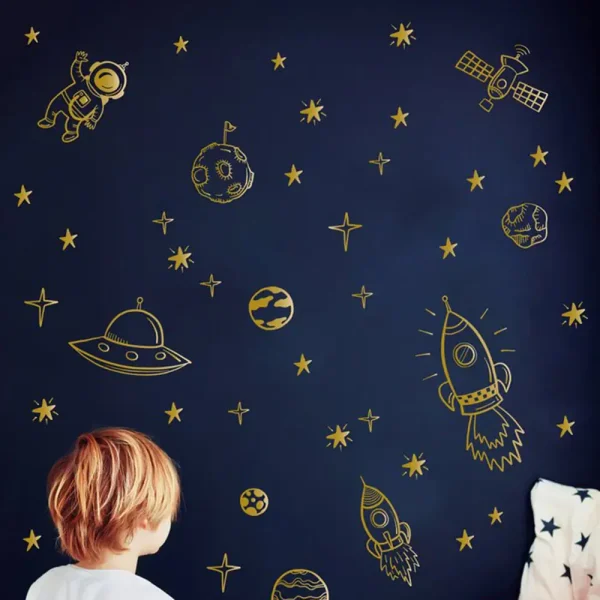 Decoração de parede com desenhos de foguetes, astronautas, planetas e estrelas em dourado sobre fundo azul escuro.