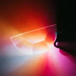 Lâmpada de plasma com efeito de luz colorida, mostrando uma linha de plasma brilhante e uma esfera parcialmente visível com cores vibrantes.