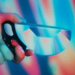 Lupa de espectro com estrutura prismática de vidro, usada para dispersar luz em cores diferentes, com fundo colorido difuso.