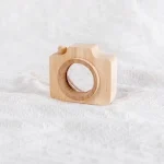 Câmera de madeira com detalhes simples, sem lentes ou botões visíveis, colocada sobre tecido branco.