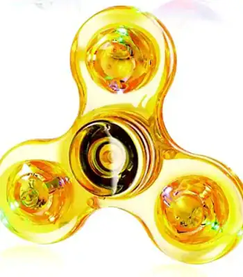 Fidget spinner dourado com três braços, cada um com uma esfera dourada e detalhes coloridos, visto de cima.
