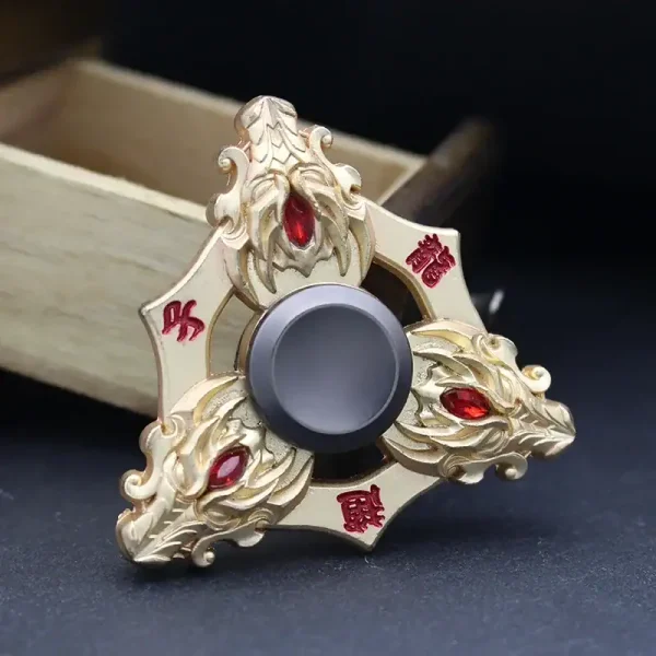 Fidget spinner decorativo com detalhes dourados e pedras vermelhas, visto de cima com fundo preto.