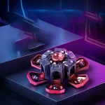 Dispositivo de física com componentes metálicos e luzes de plasma em cores rosa e azul, em ambiente escuro com iluminação de palco.