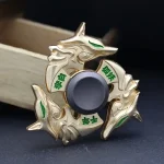Fidget spinner com design de dragão dourado, detalhes verdes e cabeça de dragão em destaque, sobre fundo escuro.