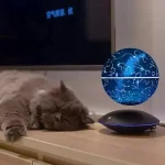 Globo terrestre representando um mapa estelar e constelações, colocado sobre uma superfície de madeira, com um gato adormecido ao lado.