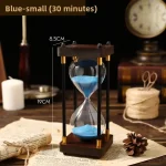 Relógio de areia azul com estrutura de madeira e suporte de metal, medindo 19cm de altura e 8,5cm de diâmetro, usado para demonstrações educativas de tempo.