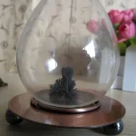 Vulcão de cinzas em miniatura com base de madeira e vidro de proteção, decorativo para ciência ou educação.