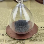 Fungo cinzento com textura fofa dentro de um frasco de vidro transparente, colocado sobre uma base de cortiça, com fundo de papel impresso.