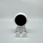 Robô de brinquedo branco com visor preto, sentado em fundo branco, com detalhes minimalistas e design futurista.