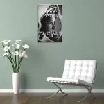 Poster de astronauta em preto e branco na parede, ao lado de uma cadeira branca de design moderno e uma planta com flores brancas em vaso alto.