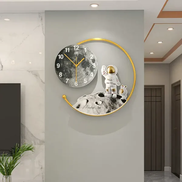 Relógio de parede com design de astronauta e lua, com elementos dourados e fundo cinza, em ambiente moderno com paredes de mármore e teto de gesso.