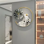Relógio de parede com design de astronauta e lua, incluindo uma esfera de relógio, uma figura de astronauta e uma lua decorativa em um círculo dourado.