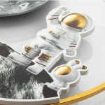 Figura de astronauta em pose de caminhada com capacete dourado e detalhes em vermelho e dourado, feita de material plástico branco.