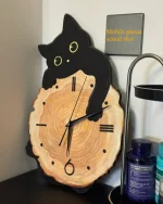 Relógio de parede com design de gato preto sobre tronco de árvore, detalhes em preto e amarelo, com caixa de bateria ao lado, em ambiente de escritório ou sala de estar.