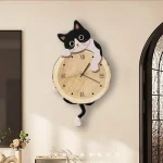 Relógio de parede com design de gato preto e branco, com expressão fofa, pendurado numa parede clara, com detalhes de escultura de gato na parte superior e inferior.